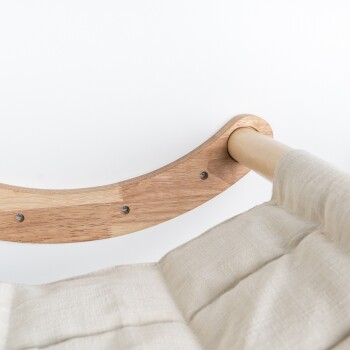 Nahaufnahme eines Holzrahmens für ein Haustierbett mit einem beigen Stoffkissen, das die gebogene Holzstütze und Schrauben zeigt.