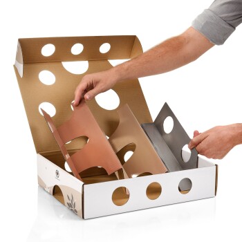 Eine Person platziert farbige Trennwände in einen Karton mit runden Löchern, der zur Organisation von Haustierbedarf gedacht ist.