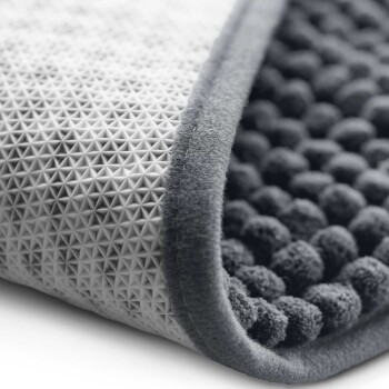 Nahaufnahme einer Tiermatte mit einer strukturierten, grauen Oberfläche mit erhöhten dreieckigen Mustern und einem weichen, plüschigen Rand.