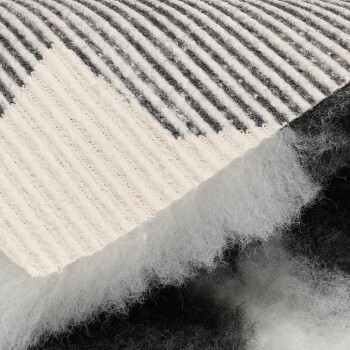 Nahaufnahme eines schwarz-weiß gestreiften Kratzpads für Haustiere mit einer weichen, flauschigen Unterseite.