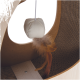 Gros plan sur un jouet pour chat avec une balle ronde beige douce avec une plume attachée, suspendue à l'intérieur d'une structure de jeu en bois pour chat.