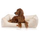 Ein brauner Irish Setter Hund, der in einem plüschigen, cremefarbenen Haustierbett mit gerippter Textur und einem kleinen Logo-Tag entspannt.