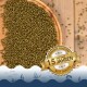 Grüne Fischfutterpellets, die auf einer Holzoberfläche verteilt sind, mit einem goldenen Abzeichen, das 'Beste Qualität' und '15 Jahre' auf Deutsch besagt.