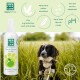 Eine Flasche MEN FOR SAN Eau de Cologne für Hunde mit einem Design von grünem Apfel neben einem schwarz-weißen Hund auf einer Wiese.