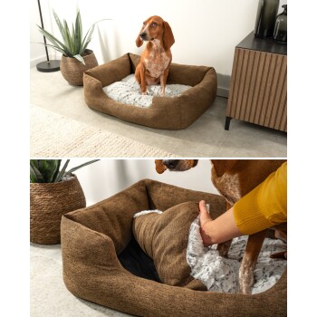 Ein braunes Hundebett mit einem weichen, plüschigen Innenraum, mit einem Hund, der darin sitzt. Eine Hand passt den Stoff des Bettes an.