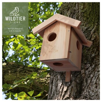 Ein hölzernes Vogelhaus, das an einem Baum montiert ist, mit dem Logo 'WILDTIER LIEBE' und dem Text 'NATUR BRAUCHT EIN ZUHAUSE.'