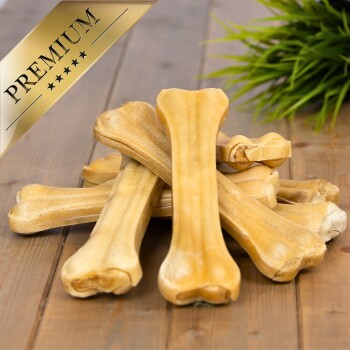 Ein Haufen hochwertiger Hundeknochen auf einer Holzoberfläche, mit einem goldenen "PREMIUM"-Etikett in der oberen linken Ecke.
