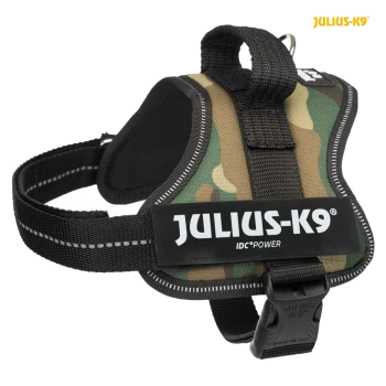 A camouflage dog harness with a black strap, featuring the brand name "JULIUS-K9" and "IDC POWER" on a prominent label.