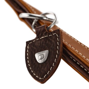 Nahaufnahme einer braunen Lederhundeleine mit einem silbernen Metallschild, das mit "HUNTER" und "JUCHTEN" geprägt ist, mit detaillierter Naht.