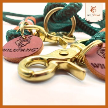Nahaufnahme einer grünen geflochtenen Haustierleine mit goldenen Metallclips und Lederetiketten, die mit "WILDFANG" geprägt sind.