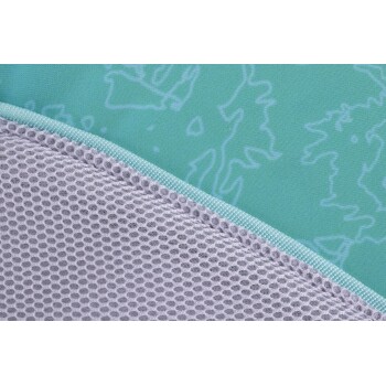 Nahaufnahme eines Haustierbettes mit einem hellblauen gemusterten Stoff oben und einem grauen Netzboden, mit einem türkisfarbenen Reißverschluss.