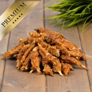 Ein Haufen hochwertiger getrockneter Fischleckerlis für Haustiere, mit einem goldenen "PREMIUM"-Etikett in der Ecke, auf einer Holzoberfläche mit grünem Gras im Hintergrund.