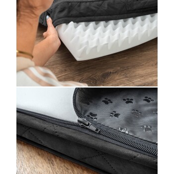 Eine Person hält ein Haustierbett mit einem grauen, gesteppten Bezug, der ein weißes, gezacktes Schauminnere zeigt. Der Boden zeigt einen Reißverschluss und ein Pfotenabdruckmuster.