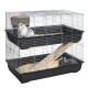 Two-level wire rabbit cage with black plastic trays, ramp, hay and two rabbits (white-gray upper, dark-gray lower).