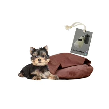 Ein kleiner Yorkshire Terrier sitzt neben einem braunen Haustierbett, mit einem Etikett, das ein Set mit Hundekotbeuteln zeigt.