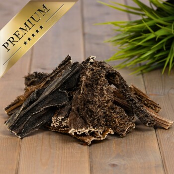 Premium-Hundekauartikel aus natürlichem Holz, mit einer Mischung aus dunklen und hellen Texturen, auf einer Holzoberfläche mit grünem Gras präsentiert.