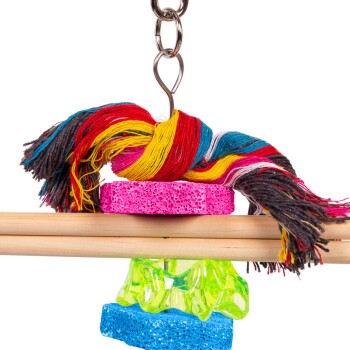 Buntes Vogelspeilzeug mit einem mehrfarbigen Seil, rosa und blauen schwammartigen Blöcken und einem grünen Kunststoffteil, das an einer Kette hängt.