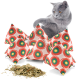 Eine graue Katze untersucht neugierig einen Haufen bunter, mit Katzenminze gefüllter Kissen mit kreisförmigen Mustern, neben losen Katzenminzeblättern.