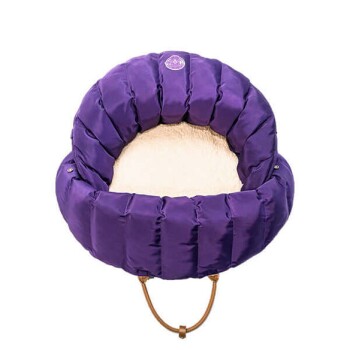 Lila Haustierbett mit plüschigem Innenraum, mit einem runden, gepolsterten Design und einem kleinen Logo oben.