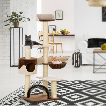 Ein moderner Kratzbaum mit einer schwarzen Katze oben und einer orangefarbenen Tabby in einer Hängematte, in einem stilvollen Wohnzimmer mit einer weißen Ziegelwand.