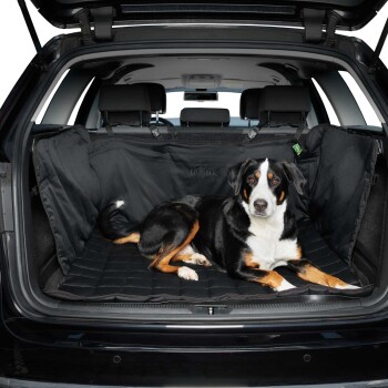 Ein schwarz-brauner Hund liegt bequem auf einer gepolsterten schwarzen Autositzabdeckung für Haustiere im hinteren Bereich eines SUVs, mit sichtbarem sauberen Innenraum.