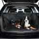 Ein schwarz-brauner Hund liegt bequem auf einer gepolsterten schwarzen Autositzabdeckung für Haustiere im hinteren Bereich eines SUVs, mit sichtbarem sauberen Innenraum.