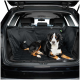 Ein schwarz-brauner Hund liegt bequem auf einer gepolsterten schwarzen Autositzabdeckung für Haustiere im hinteren Bereich eines SUVs, mit sichtbarem sauberen Innenraum.