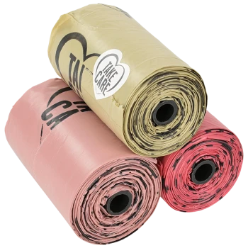 Trois rouleaux de sacs à déchets pour animaux en couleurs rose, or et rouge, avec un autocollant "Take Care" sur le rouleau doré.