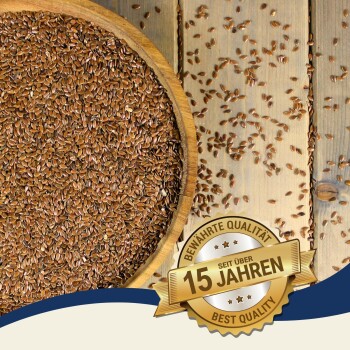 Eine Holzschale mit braunen Leinsamen, umgeben von verstreuten Samen und einem Abzeichen mit der Aufschrift "Beste Qualität" und "15 Jahre."