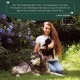 Eine Frau im Freien mit Blumen hält eine schwarze Katze, während ein wolfähnlicher Hund neben ihr liegt. Text darüber bewirbt Wolfsbacher Naturprodukte.