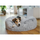 Kleiner tricolor Hund, zusammengerollt in rundem, flauschigem grauem Haustierbett auf Holzboden in einem hellen Wohnzimmer