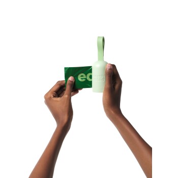 Eine Person hält einen grünen Earth Rated Hundekotbeutelspender und eine Rolle mit Kotbeuteln, die umweltfreundliche Haustierpflegeprodukte präsentiert.