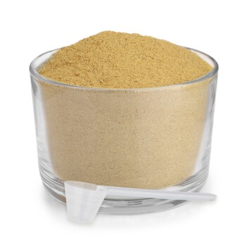 Ein Glasbehälter gefüllt mit goldbraunem Pulver, begleitet von einem kleinen weißen Messlöffel.