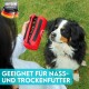 Eine Person hält einen roten Leckerli-Beutel, der mit Hundefutter gefüllt ist, während ein neugieriger Hund zu ihnen aufblickt. Der Text lautet: 'Geeignet für Nass- und Trockenfutter.'