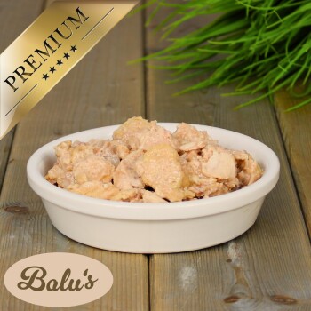 Bolu's Premium-Haustierfutter in einer weißen Schüssel, mit einer cremigen Mischung aus Fleischstücken, auf einer Holzoberfläche mit grünem Gras im Hintergrund.