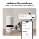 Eine Katze, die aus einem modernen automatischen Haustierfutterspender frisst, mit einem Smartphone, das die Fütterungszeitpläneinstellungen auf Deutsch anzeigt.