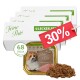 Premium Nassfutter für Hunde, serviert in einer Edelstahlschüssel auf einer Holzoberfläche mit grünem Gras im Hintergrund.