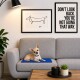 Ein kleiner Hund liegt auf einem grauen Sofa mit einer blauen Matte, umgeben von gerahmten Kunstwerken mit einer einfachen Hundeskizze und einem motivierenden Zitat.
