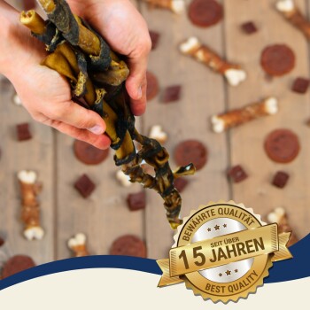 Eine Person hält einen geflochtenen Hundekauartikel zwischen verschiedenen Leckerlis auf Holz, mit einem Abzeichen, das "Beste Qualität" und "Bewährte Qualität seit über 15 Jahren" angibt.