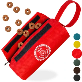 ® Futterbeutel Hund | Futterdummy Hunde | Apportierbeutel für Hunde mit Handschlaufe rot Rote Leckerlitasche für Haustiere mit schwarzen Reißverschlüssen, verstreuten braunen Leckereien und einem Logo mit einem Hund. Farboptionen auf der Seite angezeigt.