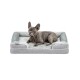 Ein Französischer Bulldogge, die auf einem plüschigen, grauen Hundebett mit einem weichen, hellgrauen Innenfutter und weißen Akzenten ruht.