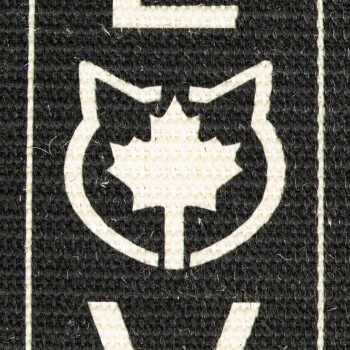 Nahaufnahme eines Logos mit einem stilisierten Katzenkopf und einem Ahornblatt im Inneren, vor einem schwarzen Hintergrund.