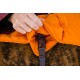 Eine Nahaufnahme einer Hand, die eine orangefarbene Haustierjacke mit einer braunen Schnalle befestigt, die auf dem Fell eines Hundes ruht.