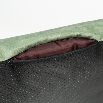 Nahaufnahme eines Haustierbettes mit einer grünen Fleece-Oberseite und einem schwarzen strukturierten Boden mit einem Reißverschluss, der ein kastanienbraunes Innenfutter zeigt.