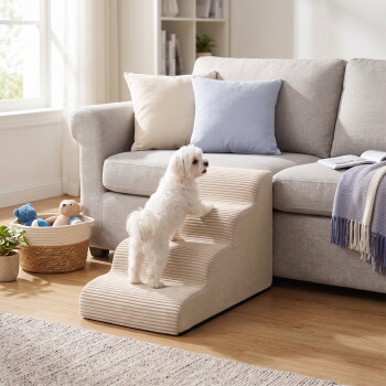 Kleiner weißer Hund steigt die beige Haustiertreppe zu einem hellgrauen Sofa mit pastellfarbenen Kissen, Spielzeugkorb und Decke in der Nähe hinauf.