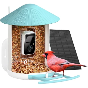 Futtersation AI im Abonnement + Solarpanel Ein bunter roter Kardinal, der auf einem Vogelhaus mit einer Kamera sitzt, umgeben von Vogelfutter und einem Solarpanel an der Seite.