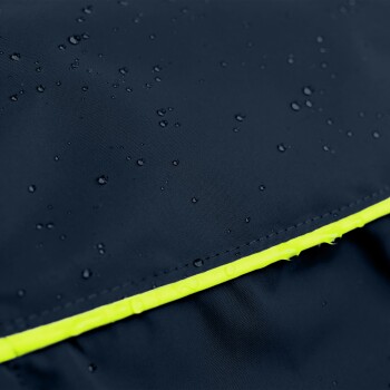 Nahaufnahme einer wasserdichten Haustierjacke in Dunkelblau mit einem hellgelben reflektierenden Streifen, mit Wassertropfen auf der Oberfläche.