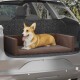 Ein glücklicher Corgi, der auf einem braunen Haustierbett im hinteren Teil eines Autos entspannt, mit einem grauen gemusterten Hintergrund und einem sonnigen Ausblick nach draußen.