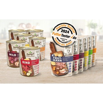 Dosen und Beutel von Betty's Landhausküche Hundefutter, mit Geschmacksrichtungen wie Wild, Rind und Truthahn, mit einem Qualitätssiegel für 2024.