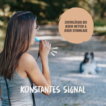 Eine Frau mit einer blauen Pfeife steht auf einem Weg mit einem Hund. Text: 'ZUVERLÄSSIG BEI JEDERM WETTER & JEDER STIMMLAGE' und 'KONSTANTES SIGNAL.'